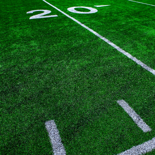 Football field turf with yard lines and the 20-yard marker representing a custom football team intro voiceover.