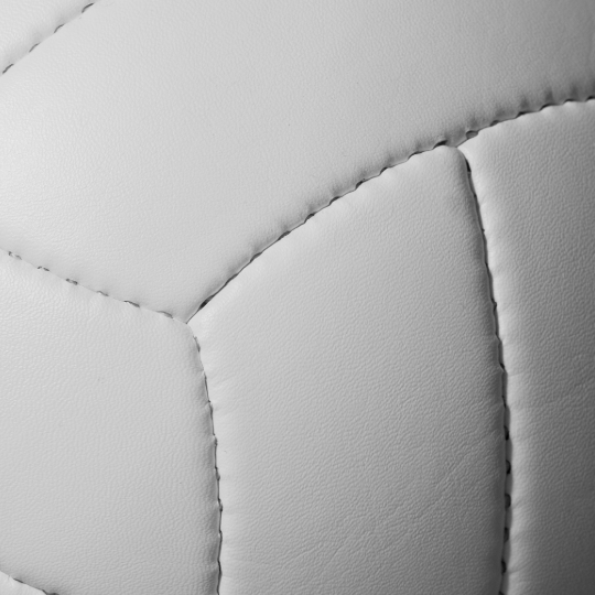 Close-up of a white volleyball with stitched panels and leather texture, representing a custom volleyball team introduction