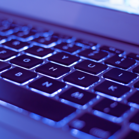 Close-up of a backlit mac laptop keyboard with blue tint symbolizing online submission for a custom voiceover order.